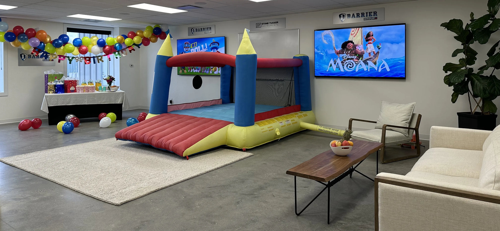 Room with bouncy castle, happy birthday banner, and balloons